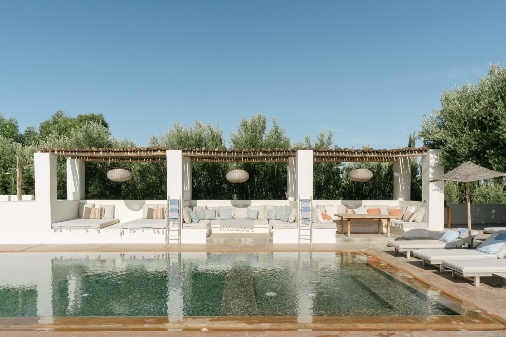 Le salon extérieur sous la pergola au bord de la piscine