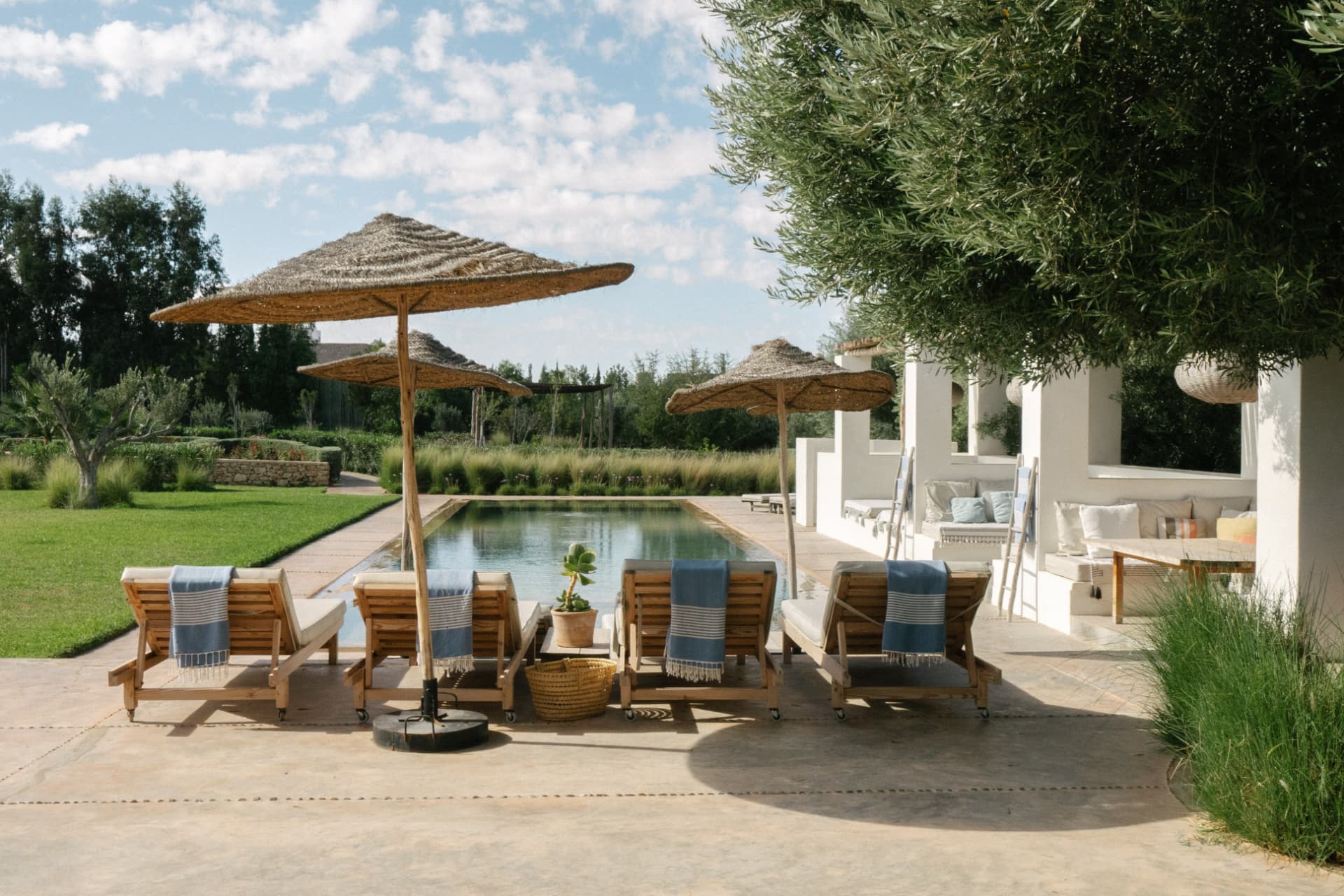 Les transats et parasols en paille au bord de la piscine
